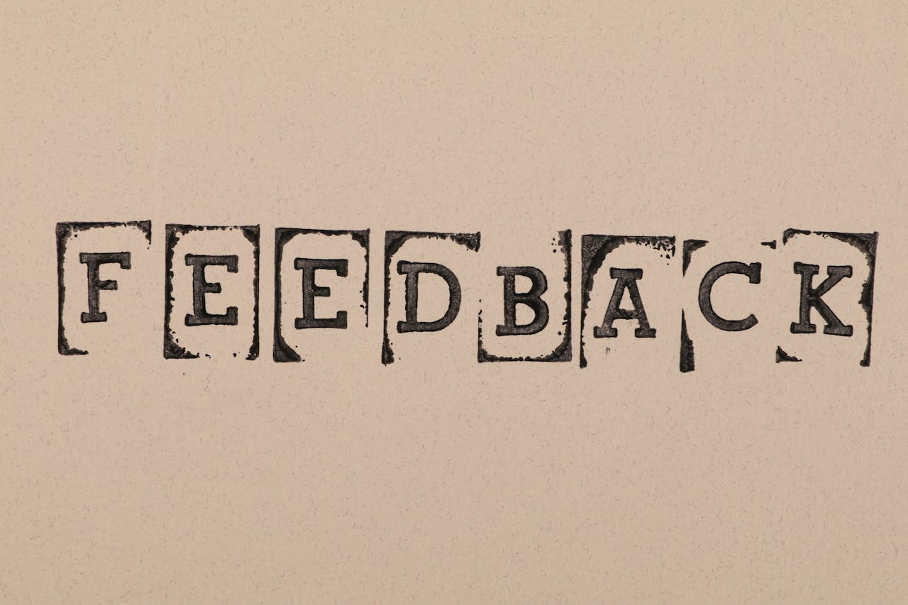 Vintage-style stamped letters spelling Feedback on textured paper background.